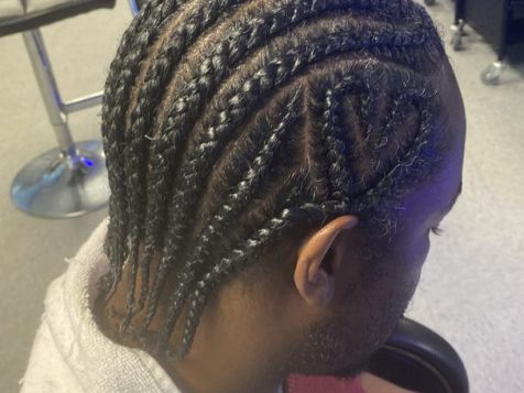 A close-up of neatly braided hair styled in rows, showcasing intricate patterns in a vibrant salon setting.